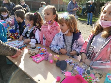 Sremska Mitrovica, 9 October 2020. School fair. Children sell toys, books and school supplies to customers. Play behavior. Exhibition - sale of children's things. Schoolchildren stand near tables in the school yard