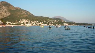 Sutomore, Karadağ, 08.08.205: Adriyatik Denizi boyunca rahatlatıcı anlar. Tekneler sakin sularda yelken açar. Arka planda görkemli dağlar, berrak mavi bir gökyüzünün altında.