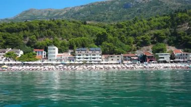 Sutomore, Karadağ, 08.08.205: Adriyatik Denizi boyunca rahatlatıcı anlar. Tekneler sakin sularda yelken açar. Arka planda görkemli dağlar, berrak mavi bir gökyüzünün altında..