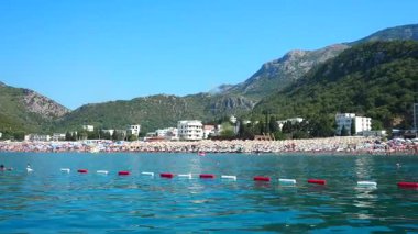 Canj, Karadağ 08.10.2025: Sıcak güneş ışığı, berrak mavi sular ve hafif dalgalar mükemmel bir gün yaratıyor. Ziyaretçiler kıyı şeridinde dinlenirken, diğerleri çarpıcı manzaralarla çevrili Adriyatik Denizi 'nde yüzüyor.