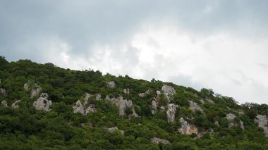 Yoğun yeşilliklerle kaplı görkemli tepeler ufuk boyunca uzanıyor. Yumuşak bulutlar tepemizde beliriyor. Gün boyunca sakin ve huzurlu bir atmosfer yaratıyor. Elektrik hatları ve elektrik kabloları.