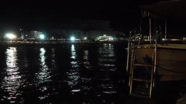 Dalgalar yavaşça kumlu sahile vururken yakındaki binaların ışıkları Adriyatik Denizi 'ni yansıtıyor..