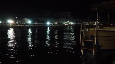 Canj, Chanj, Karadağ, 08.05.2025: Sahilde sakin bir gecede şehrin ışıkları Adriyatik Denizi 'ni yansıtırken kıyıya vuran dalgaların sakinleştirici seslerinin tadını çıkarın.