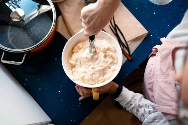 Cheesecake 'in malzemelerini kaseye karıştıran bir kadının görüntüsü.