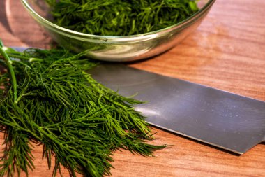 Tahta üzerinde bahçeden yeşil dereotu bir bıçakla kesilmiş