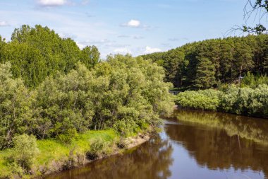 Ağaçların mavi gökyüzüne karşı yansımasıyla ormanın etrafında küçük bir nehir akar. Sibirya 'nın doğası böyle..