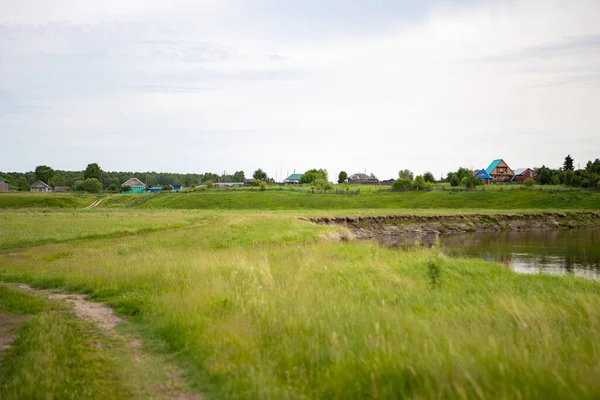 村はシベリアのオムスク地方のタラ川の近くの丘の上に立っています 崖の上に個人宅 貯水池の近くの農村部 川は牧草地や森林を流れている — ストック写真