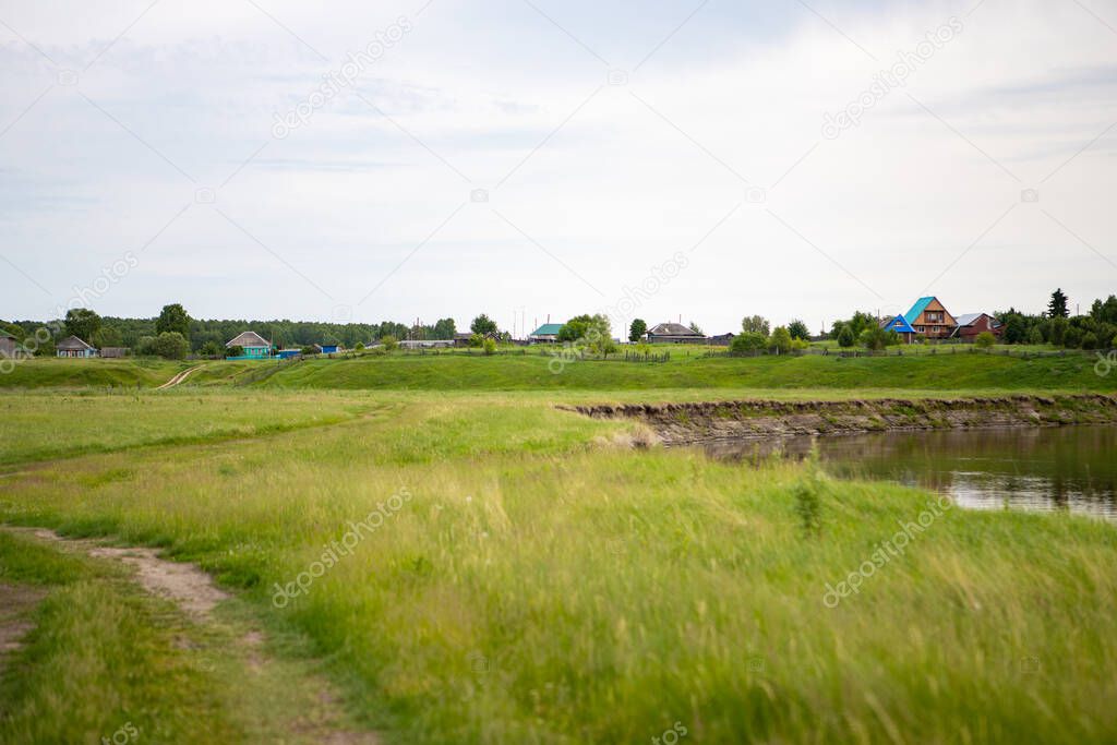 The village stands on a hill near the Tara river, Omsk region, Siberia. Private homes, rural area near the reservoir, on a cliff. The river flows through meadows and forests.