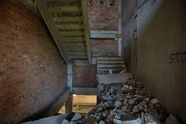 A ruined, crumbling staircase in an abandoned building. A flight of stairs collapsed in the entrance of an unfinished house