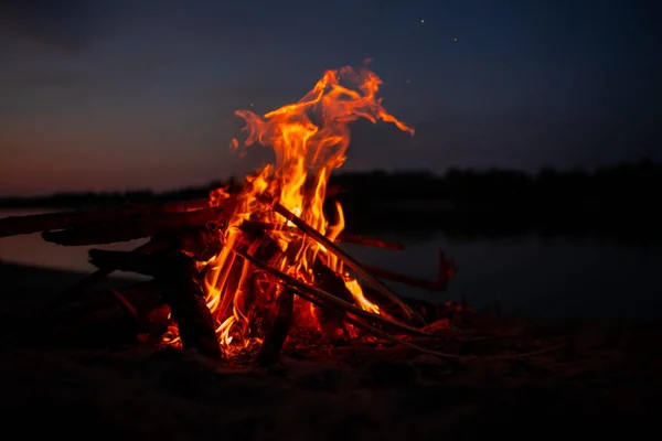 晚上在河岸上的篝火夏天在水库附近燃烧的树枝和木柴燃起的红色火焰 炉边的户外娱乐活动 — 图库照片