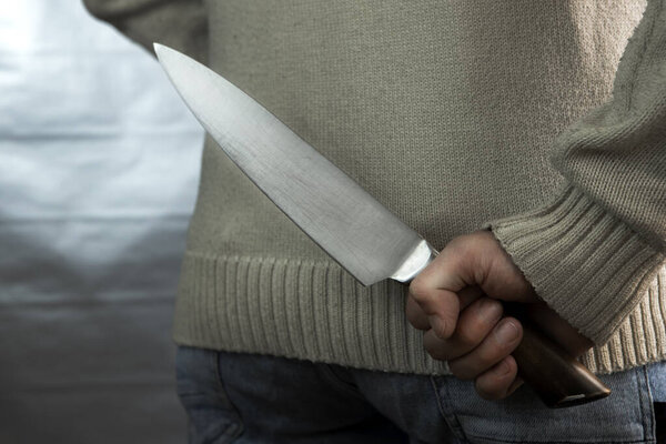 Злой человек держит нож за спиной, ожидая жертву. Маньяк и насильник с пистолетом.