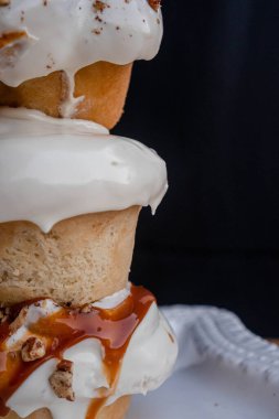 Beyaz tabakta ceviz ve karamelaya bulanmış beyaz şekerle kaplı nefis ev yapımı tarçın ruloları ve siyah sırtüstü ve mutfak ve sanatsal konsept..