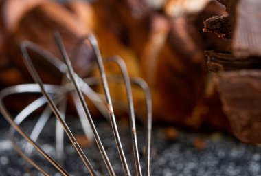 Gümüş mutfak el mikseri, arka planda ve yakın planda bir tavayla un tozuna bulanmış siyah bir masanın üzerinde..