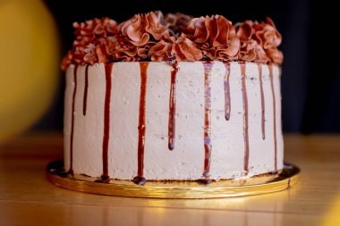 Nefis ev yapımı çikolatalı pasta, üstünde çikolata kreması, altında da beyaz krema, ahşap bir masanın üstünde ve yakın planda..