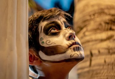 Mexican boy with traditional Day of the Dead skull makeup in close up. clipart