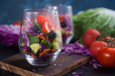 Bir beton zemin üzerine sebzeli natürmort. Taze sebze bir cam kaba dilimlenmiş