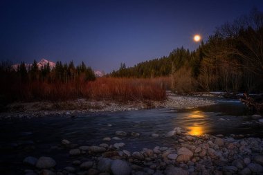 Krivan kalkanı ve dolunay bir dağ nehrinin üzerinde.
