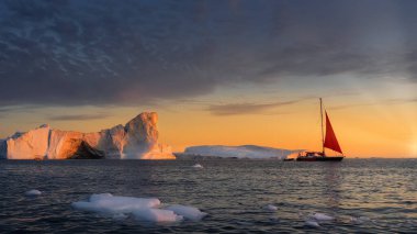 Grönland Ilulissat buzulları okyanusta kırmızı yelkenli tekneyle