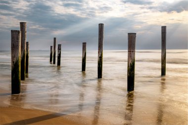 Hollanda kıyıları deniz seviyesinin altında, gün batımında ahşap dikey