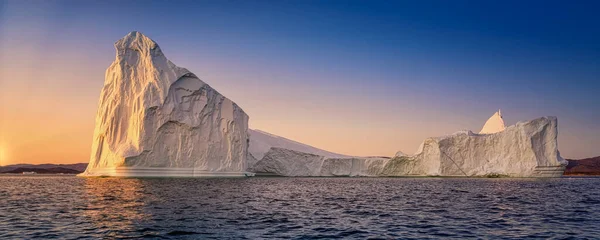 Kutup gecesinde batan güneşin ışınlarında yüzen buzullar — Stok fotoğraf