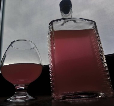 Şişe ve bir bardak rom pencerenin yanında duruyor.