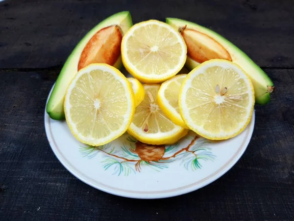 Plato Con Dos Rebanadas Aguacate Rodajas Limón Está Sobre Mesa — Foto de Stock