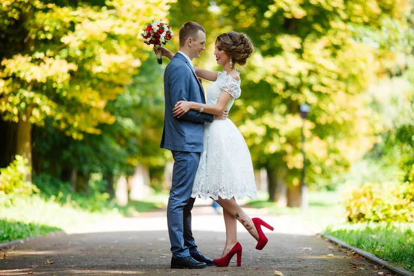 Fabelhaftes junges Hochzeitspaar posiert an einem sonnigen Tag im Park. — Stockfoto