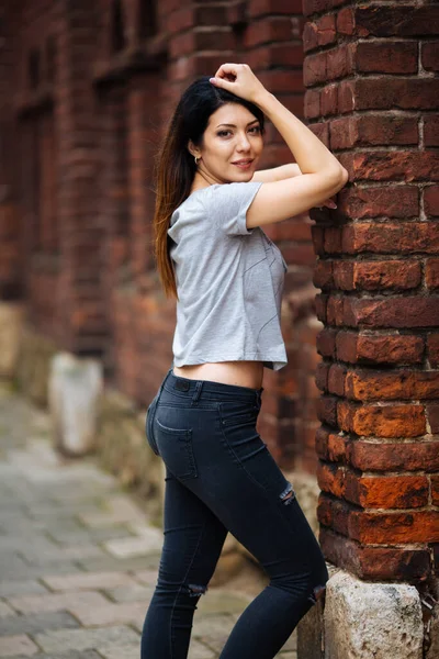 Beautiful girl near the wall in jeans — Stock Photo, Image