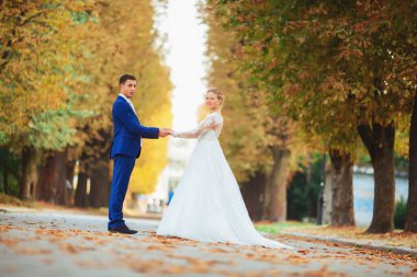 Düğün çifti, beyaz gelinlik içinde gelin ve damat ormanda yürüyor, dans ediyor ve gülümsüyor.
