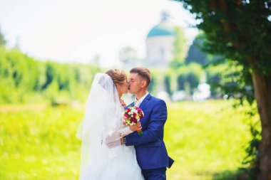 Şık gelin ve damat düğün günü dışarıda birlikte poz veriyorlar.