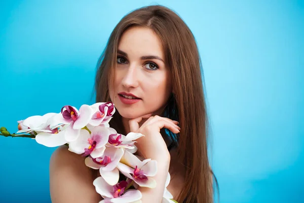 Porträtt av en flicka i baddräkt med en orkidé på vit bakgrund. Sensuell sexig tjej — Stockfoto