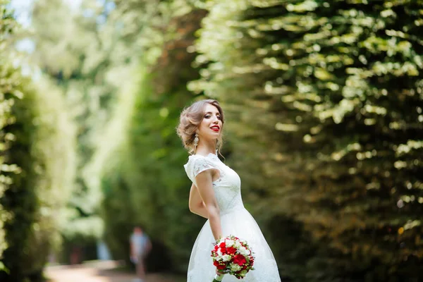 美丽的新娘，手里拿着结婚花束，站在公园外面. — 图库照片