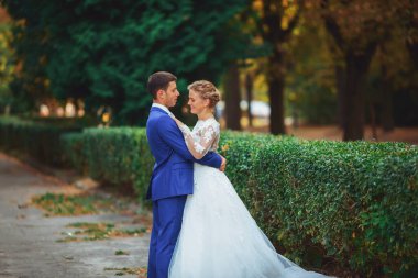 Şık gelin ve damat düğün günü dışarıda birlikte poz veriyorlar.