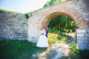 Şık gelin ve damat düğün günü dışarıda birlikte poz veriyorlar.