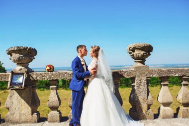 Şık gelin ve damat düğün günü dışarıda birlikte poz veriyorlar.