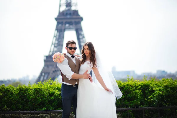 Bride and groom having a romantic moment on their wedding day in Paris, in front of the Eiffel tour