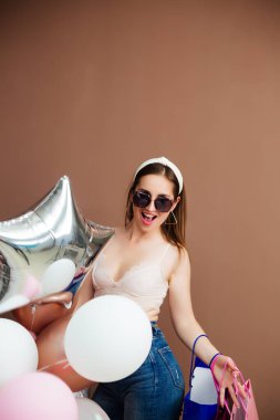 Yazlık mayo ve güneş gözlüğü takmış, gülümseyen esmer kız portresi.