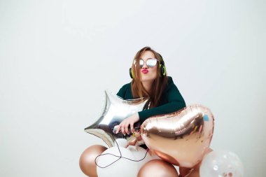 Mutlu bir kadın, balonlar ve beyaz bir duvar arkasında