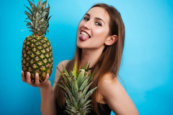 Sexy dziewczyna w kąpielówkach trzymając dojrzały ananas, odizolowany na niebiesko — Zdjęcie stockowe