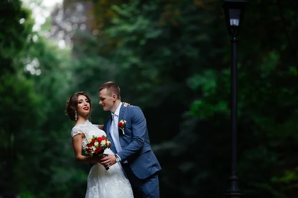 Fabelhaftes junges Hochzeitspaar posiert an einem sonnigen Tag im Park. — Stockfoto