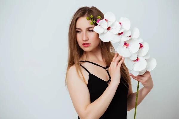 Donna che tiene un'orchidea su uno sfondo bianco — Foto Stock