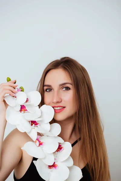Portrait of a girl in a bathing suit holding an orchid on a white background. Sensual sexy girl — Stock Photo, Image