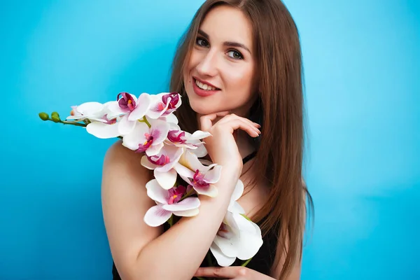 Porträtt av en flicka i baddräkt med en orkidé på vit bakgrund. Sensuell sexig tjej — Stockfoto