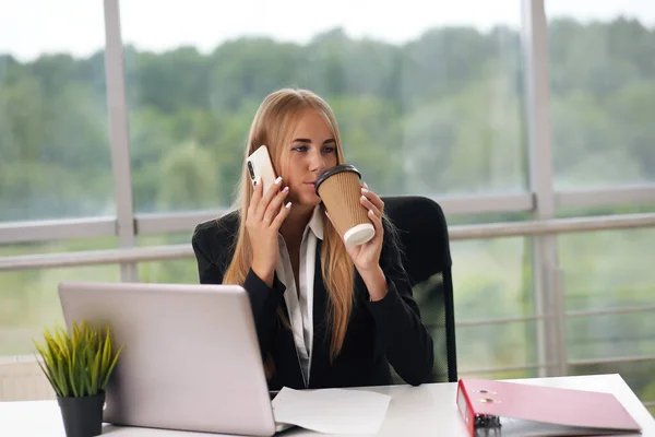 Blondynka rozmawia przez telefon pijąc kawę — Zdjęcie stockowe