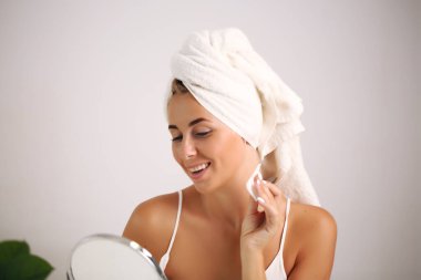 Gülümseyen kız pamuk pedlerle makyajı temizliyor.