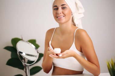 Bornozlu genç kadın, banyoya güzellik getiriyor.