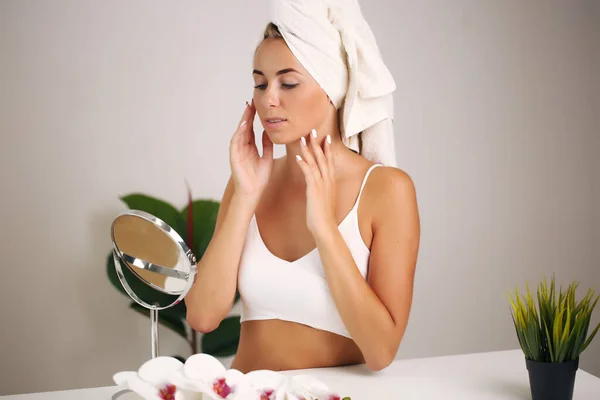 Potret seorang wanita cantik menerapkan krim wajah untuk perawatan kulit — Stok Foto
