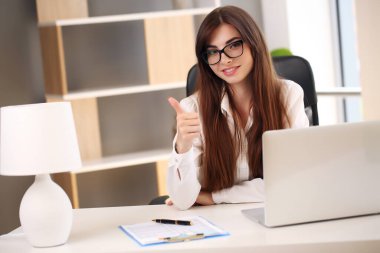 Kız evde dizüstü bilgisayarla çalışıyor ve gülümsüyor, ceketli esmer.