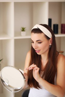 Güzellik, cilt bakımı ve insan konsepti. Gülümseyen genç kız, odadaki yüz için güzellik öneriyor.