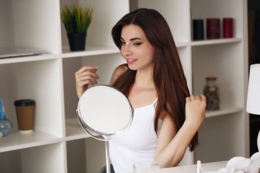 Mutlu genç bir kadın sabah sağlıklı cilt bakımı için yüz kremi sürüyor.